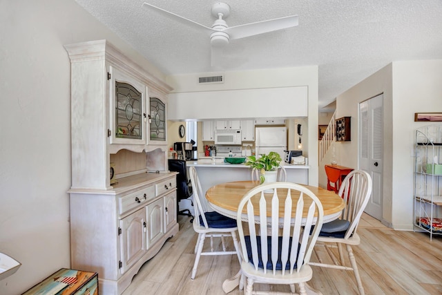 dining room featuring a textured ceiling, light hardwood / wood-style flooring, and ceiling fan