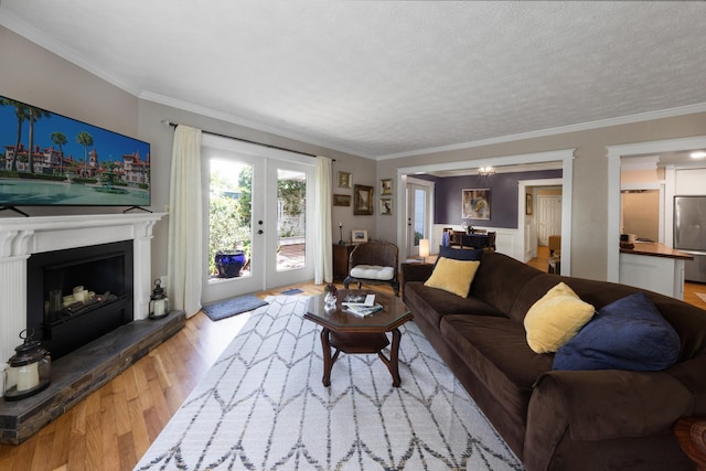 6 E Park Ave, Saint Augustine, FL 32084 - living room with french doors, wood finished floors, crown molding, a textured ceiling, and a fireplace with raised hearth
