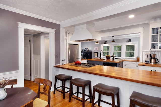 6 E Park Ave, Saint Augustine, FL 32084 - kitchen with butcher block countertops, stainless steel appliances, light wood-type flooring, white cabinets, and glass insert cabinets