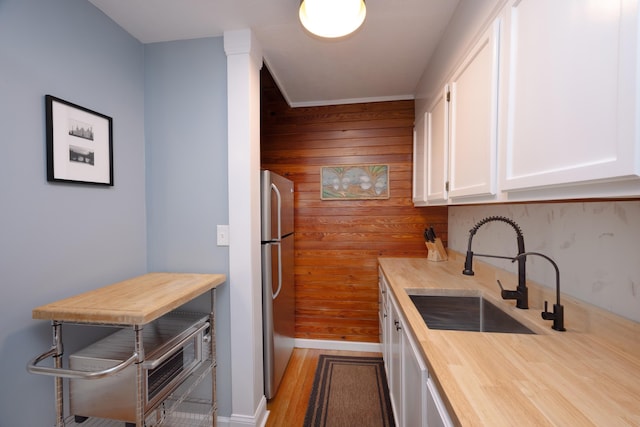 6 E Park Ave, Saint Augustine, FL 32084 - kitchen featuring butcher block countertops, freestanding refrigerator, wood walls, white cabinetry, and wood finished floors