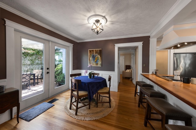 6 E Park Ave, Saint Augustine, FL 32084 - dining space with ornamental molding, light wood-style flooring, a textured ceiling, and a wainscoted wall