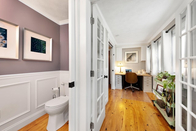6 E Park Ave, Saint Augustine, FL 32084 - bathroom featuring french doors, crown molding, hardwood / wood-style flooring, wainscoting, and a decorative wall