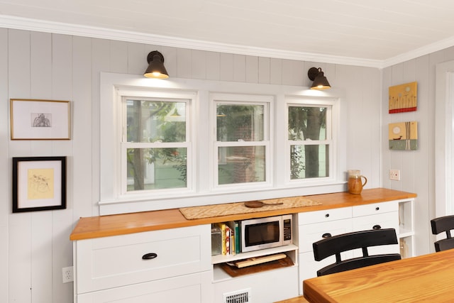 6 E Park Ave, Saint Augustine, FL 32084 - kitchen with butcher block counters, stainless steel microwave, ornamental molding, white cabinetry, and a desk
