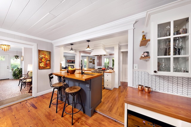 6 E Park Ave, Saint Augustine, FL 32084 - kitchen featuring butcher block countertops, crown molding, a breakfast bar, light wood-type flooring, and white cabinets
