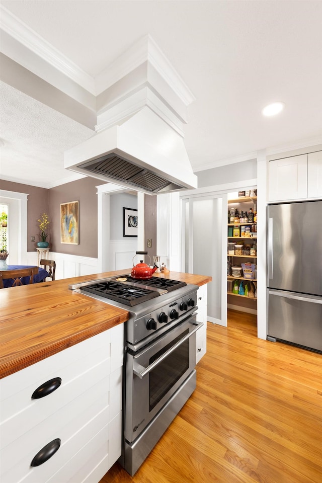 6 E Park Ave, Saint Augustine, FL 32084 - kitchen featuring appliances with stainless steel finishes, wooden counters, white cabinets, light wood-style floors, and ornamental molding