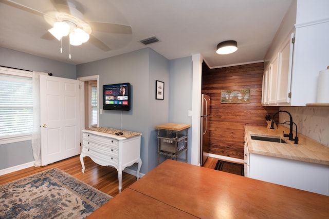 6 E Park Ave, Saint Augustine, FL 32084 - kitchen featuring freestanding refrigerator, wood finished floors, white cabinetry, wooden walls, and ceiling fan