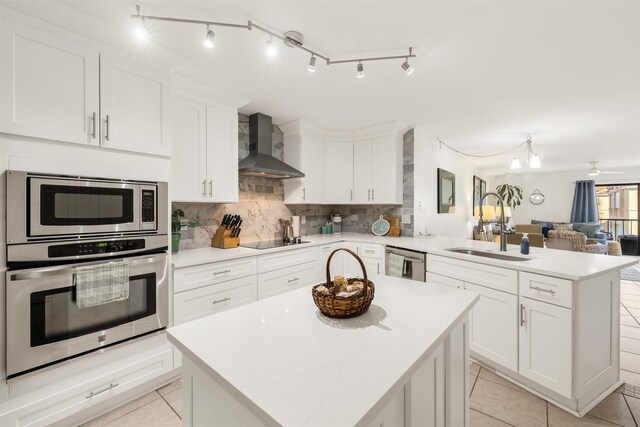 205 Pacifica Vista Way, Saint Augustine, FL 32080 - kitchen with wall chimney range hood, a peninsula, stainless steel appliances, a sink, and open floor plan