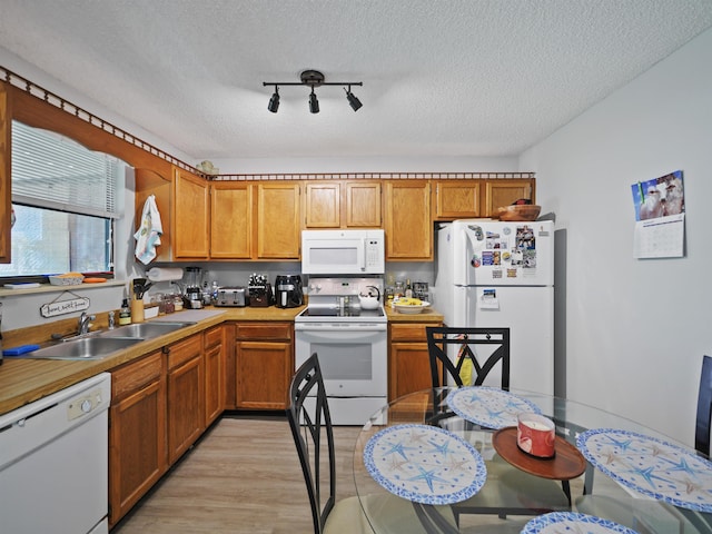 kitchen featuring a textured ceiling, light wood-type flooring, white appliances, and sink