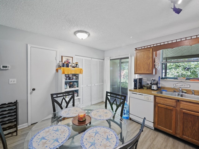 kitchen with a textured ceiling, white dishwasher, light hardwood / wood-style flooring, and sink