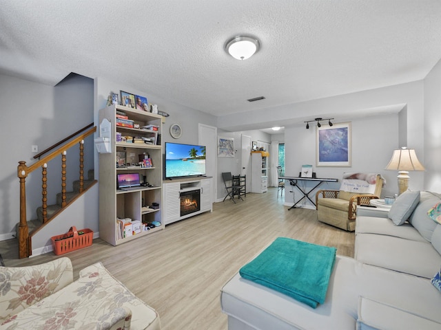 living room with a textured ceiling and light wood-type flooring