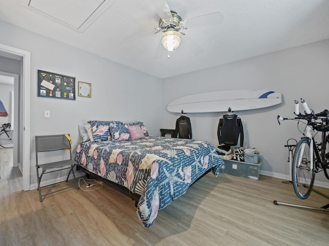 bedroom featuring ceiling fan, hardwood / wood-style floors, and a textured ceiling