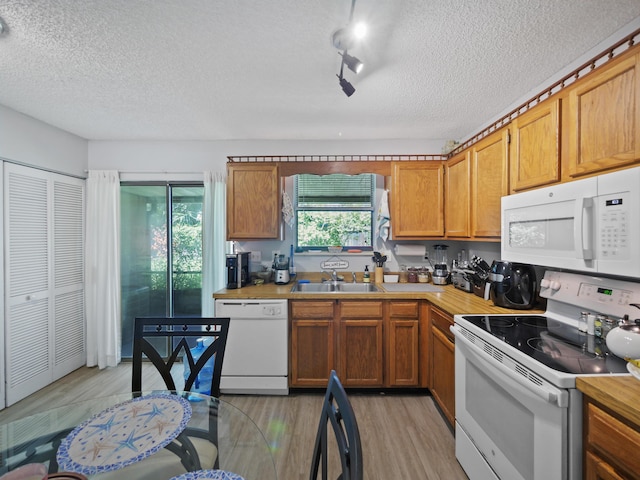 kitchen featuring a textured ceiling, light hardwood / wood-style flooring, white appliances, and sink