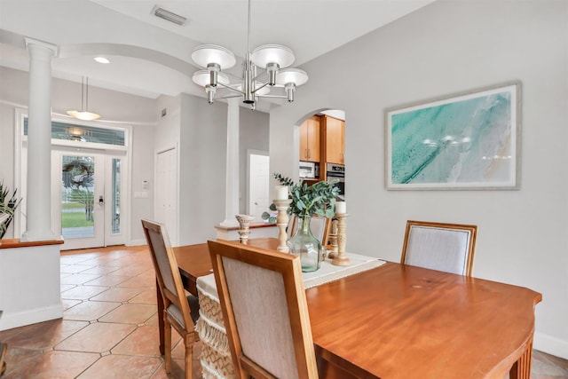 dining room featuring ornate columns, light tile patterned floors, and an inviting chandelier