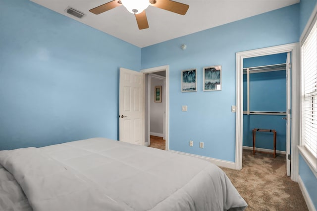 bedroom with multiple windows, a closet, light colored carpet, and ceiling fan