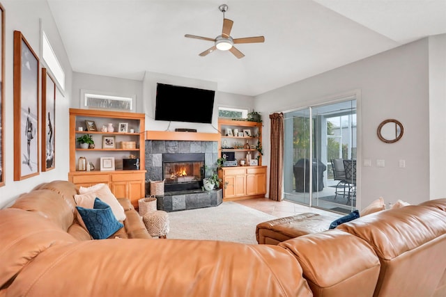 tiled living room featuring ceiling fan and a tile fireplace