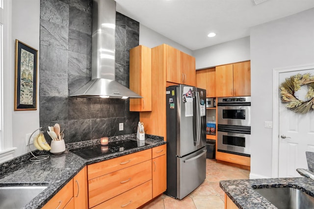 kitchen with decorative backsplash, appliances with stainless steel finishes, dark stone counters, and wall chimney range hood