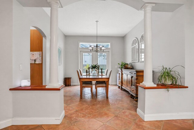 tiled dining space with decorative columns and a chandelier