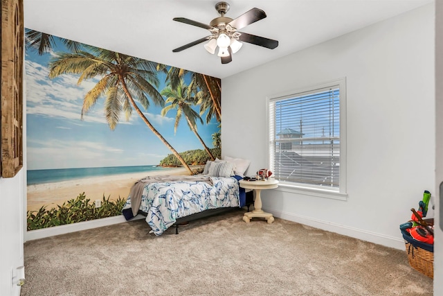 bedroom with carpet flooring, ceiling fan, a water view, and a view of the beach