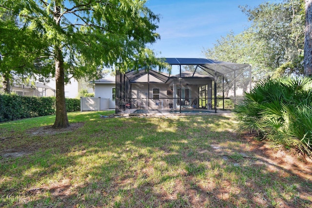 back of house featuring a lawn and glass enclosure