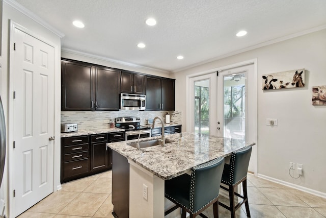 kitchen with a kitchen bar, appliances with stainless steel finishes, a kitchen island with sink, crown molding, and sink