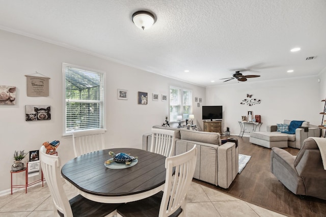 tiled dining room featuring a textured ceiling, ceiling fan, and crown molding