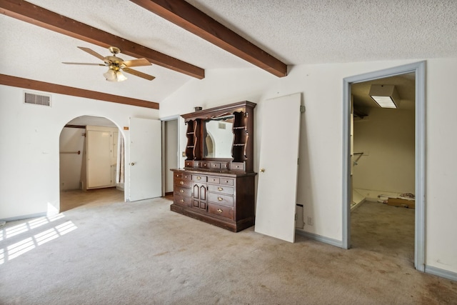 unfurnished living room featuring ceiling fan, lofted ceiling with beams, a textured ceiling, and light carpet