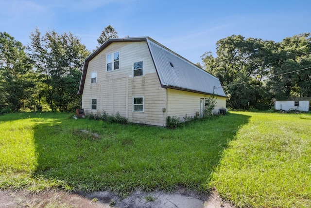 view of side of home featuring a lawn and central AC