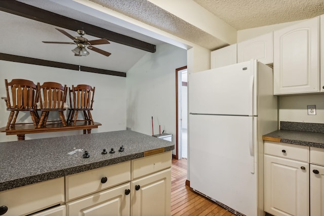 kitchen with white cabinets, lofted ceiling with beams, ceiling fan, light hardwood / wood-style floors, and white fridge