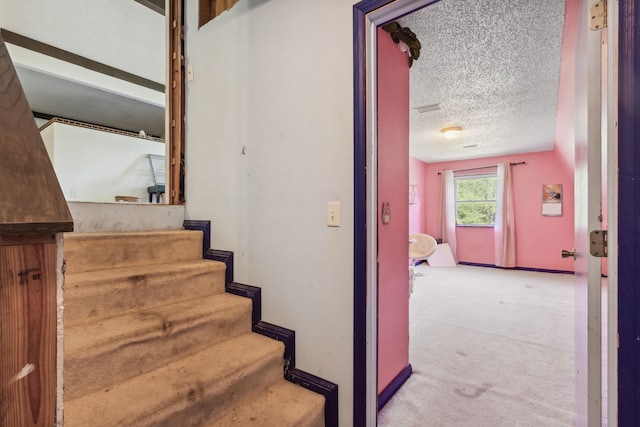 stairs featuring carpet floors and a textured ceiling