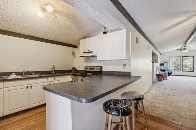 kitchen featuring light wood-type flooring, electric range oven, sink, lofted ceiling with beams, and white cabinets