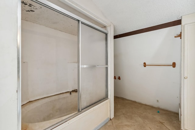 bathroom with tile patterned floors, enclosed tub / shower combo, and a textured ceiling