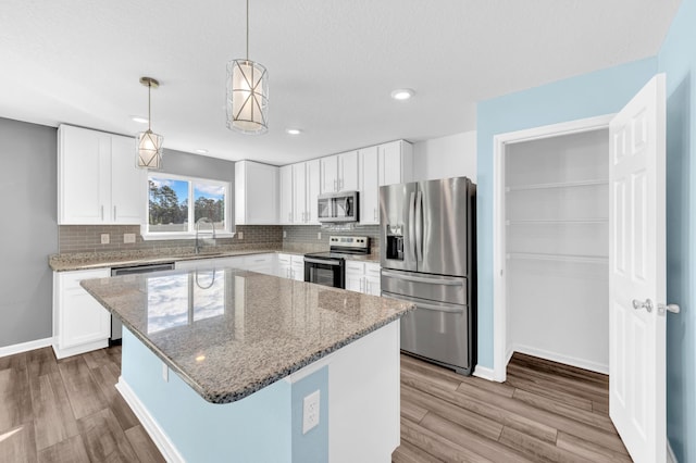 kitchen with white cabinetry, a kitchen island, light wood-type flooring, and appliances with stainless steel finishes