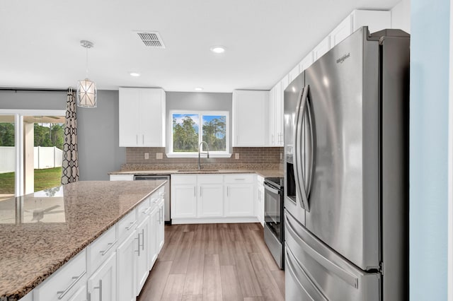 kitchen with appliances with stainless steel finishes, light wood-type flooring, white cabinetry, and sink