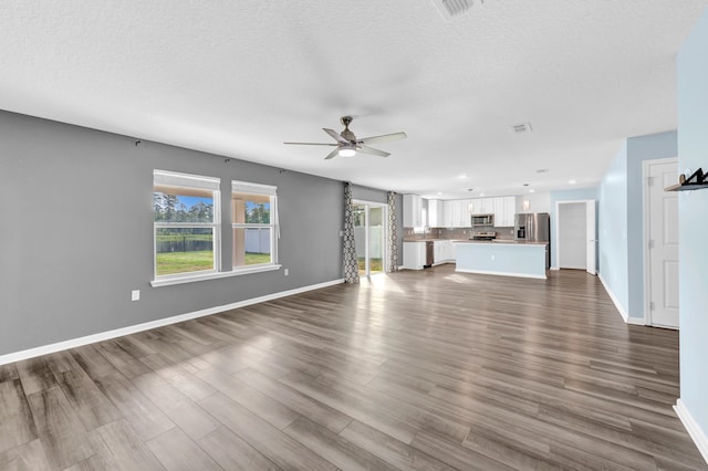 unfurnished living room with ceiling fan, dark hardwood / wood-style flooring, and a textured ceiling