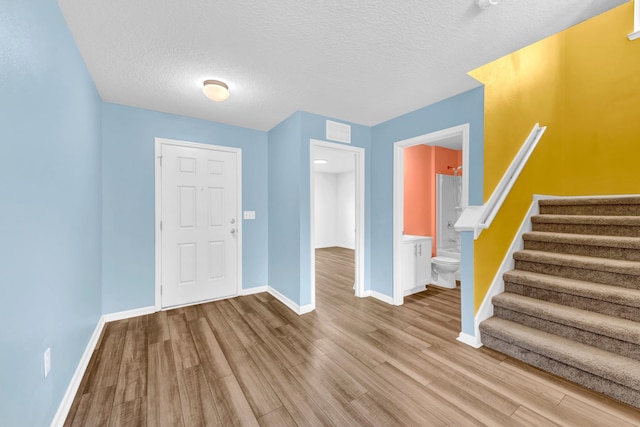 foyer entrance with hardwood / wood-style flooring and a textured ceiling