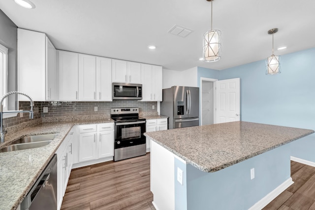 kitchen with white cabinets, sink, light wood-type flooring, decorative light fixtures, and stainless steel appliances