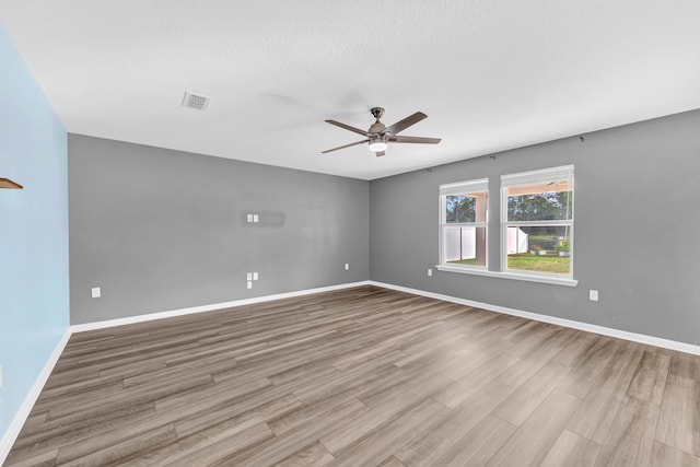 unfurnished room with ceiling fan, light wood-type flooring, and a textured ceiling