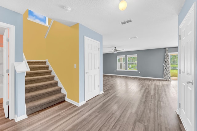 unfurnished living room with hardwood / wood-style floors, a textured ceiling, and ceiling fan