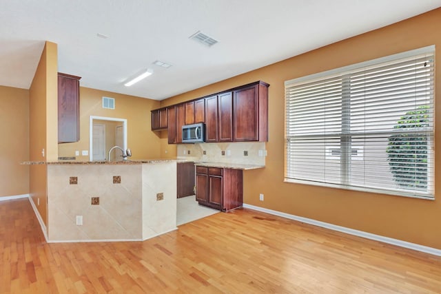 902 Heron Point Cir, Deland, FL 32724 - kitchen with stainless steel microwave, light wood-style floors, light stone countertops, and baseboards