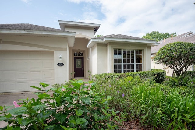 902 Heron Point Cir, Deland, FL 32724 - doorway to property featuring an attached garage, stucco siding, and a shingled roof