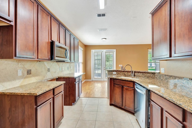 902 Heron Point Cir, Deland, FL 32724 - kitchen featuring a sink, stainless steel appliances, light stone counters, decorative backsplash, and a peninsula