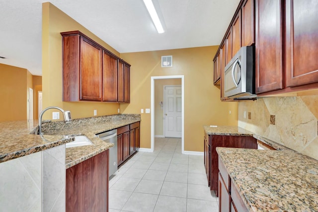 902 Heron Point Cir, Deland, FL 32724 - kitchen featuring appliances with stainless steel finishes, a sink, light stone counters, a peninsula, and baseboards