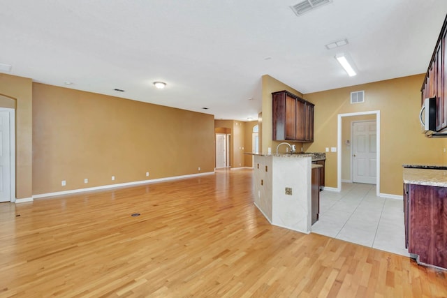 902 Heron Point Cir, Deland, FL 32724 - kitchen with stainless steel microwave, light wood finished floors, light stone countertops, baseboards, and open floor plan