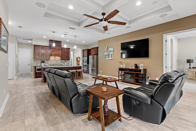 living room with coffered ceiling, ceiling fan, crown molding, and light hardwood / wood-style flooring