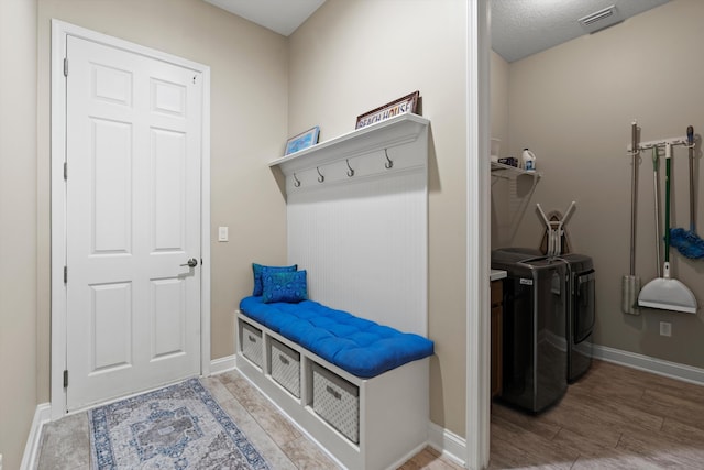 mudroom with hardwood / wood-style floors, independent washer and dryer, and a textured ceiling