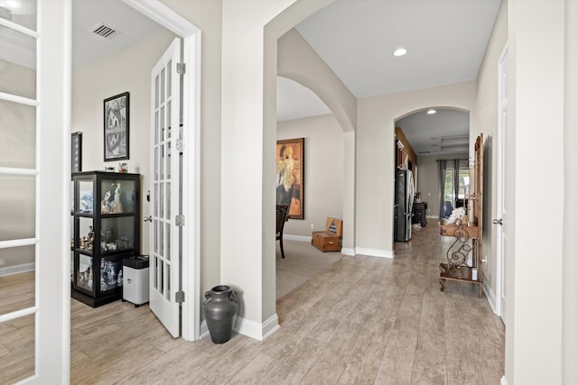 hall with light hardwood / wood-style floors and french doors