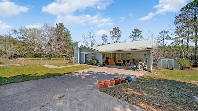 11519 W Confederate Dr, Glen Saint Mary, FL 32040 - back of house featuring a storage unit, a lawn, driveway, metal roof, and an attached carport