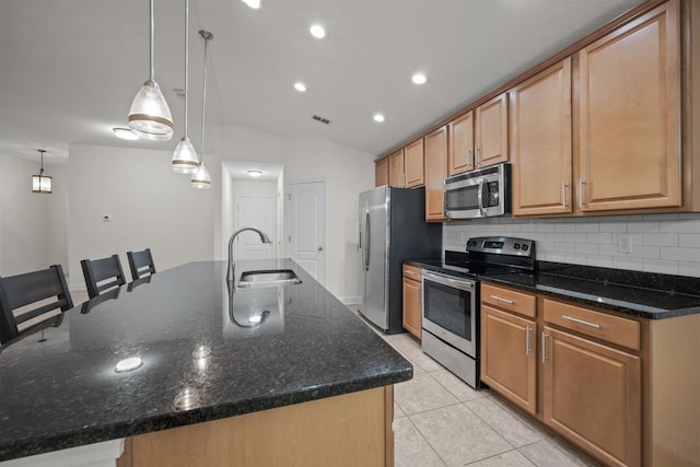 kitchen with visible vents, light tile patterned flooring, a large island with sink, a sink, and appliances with stainless steel finishes