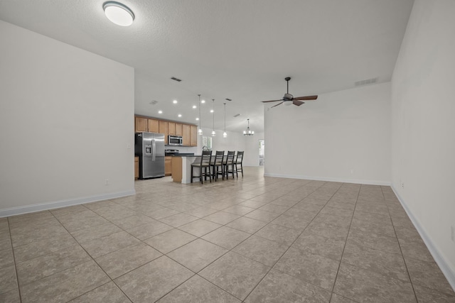 unfurnished living room featuring light tile patterned floors, visible vents, baseboards, and a ceiling fan