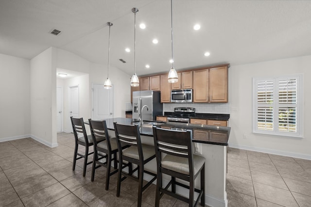 kitchen with visible vents, a center island with sink, dark countertops, stainless steel appliances, and decorative backsplash